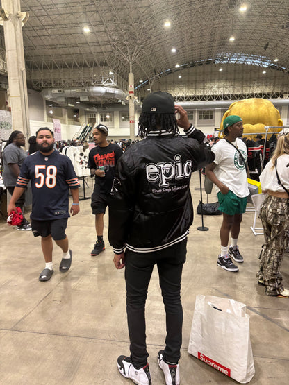 Person wearing an Epic Satin Bomber jacket at a lively event, showcasing style and culture.